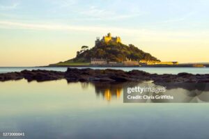 MARAZION, ENGLAND 04TH JULY 2018 - Landscape of St Michael's Mount tidal island at high tide with reflection in rock pool and Church and Castle in view, Cornwall, United Kingdom.